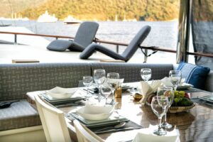 Aft deck alfresco dining table and lounge area on charter boat Caustic.
