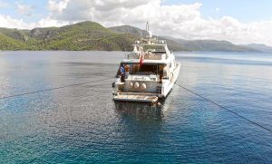 Luxury motor yacht Aden cruising swiftly in the crystal-clear turquoise waters of Göcek, Turkey.