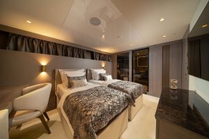 Luxuriously appointed guest cabin aboard luxury sailing yacht Nocturno featuring rich wood finishes and premium bedding.